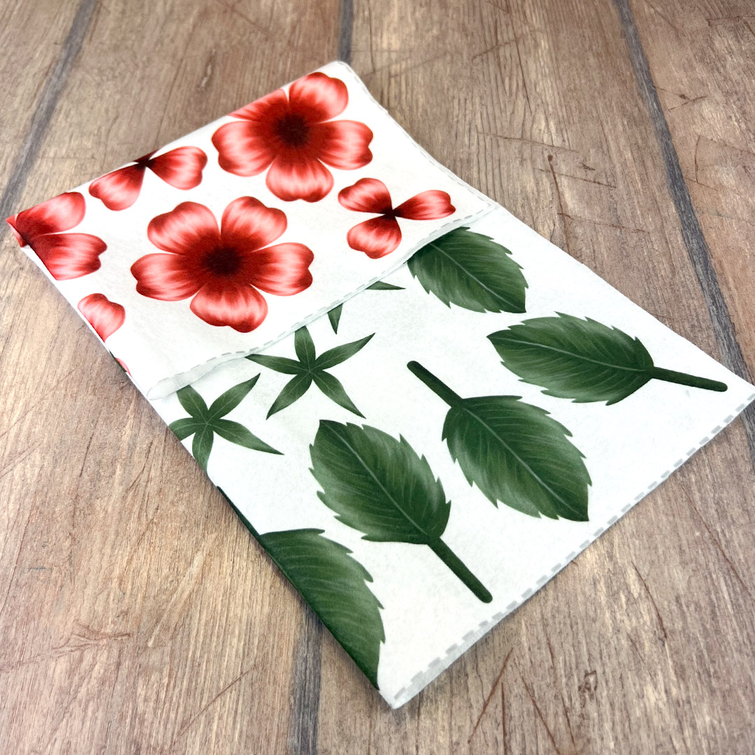 Tovagliolo bianco con fiori rossi e foglie verdi