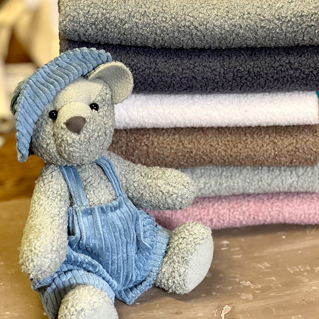 Orsetto peluche davanti a pile di asciugamani colorati