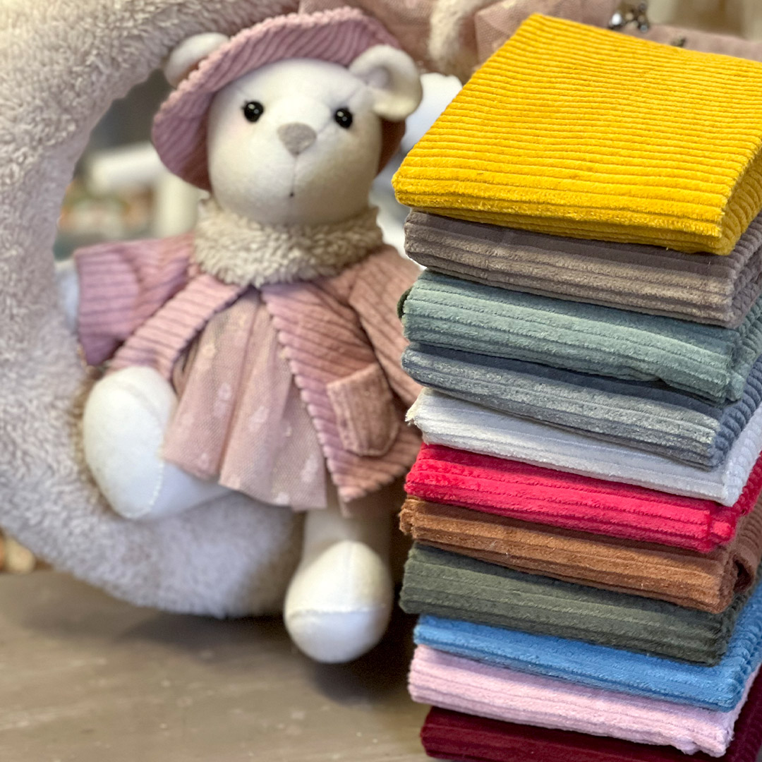Orsetto di peluche con tessuti colorati impilati