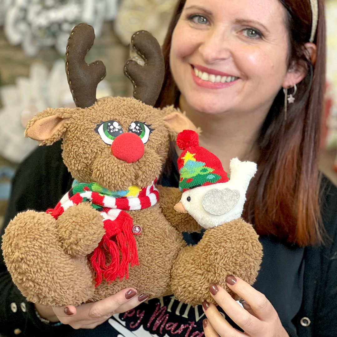 Donna sorride con pupazzi natalizi di peluche