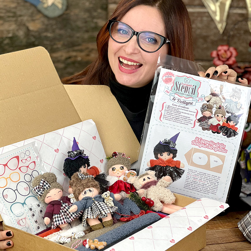 Donna mostra kit artigianale con bamboline fatte a mano
