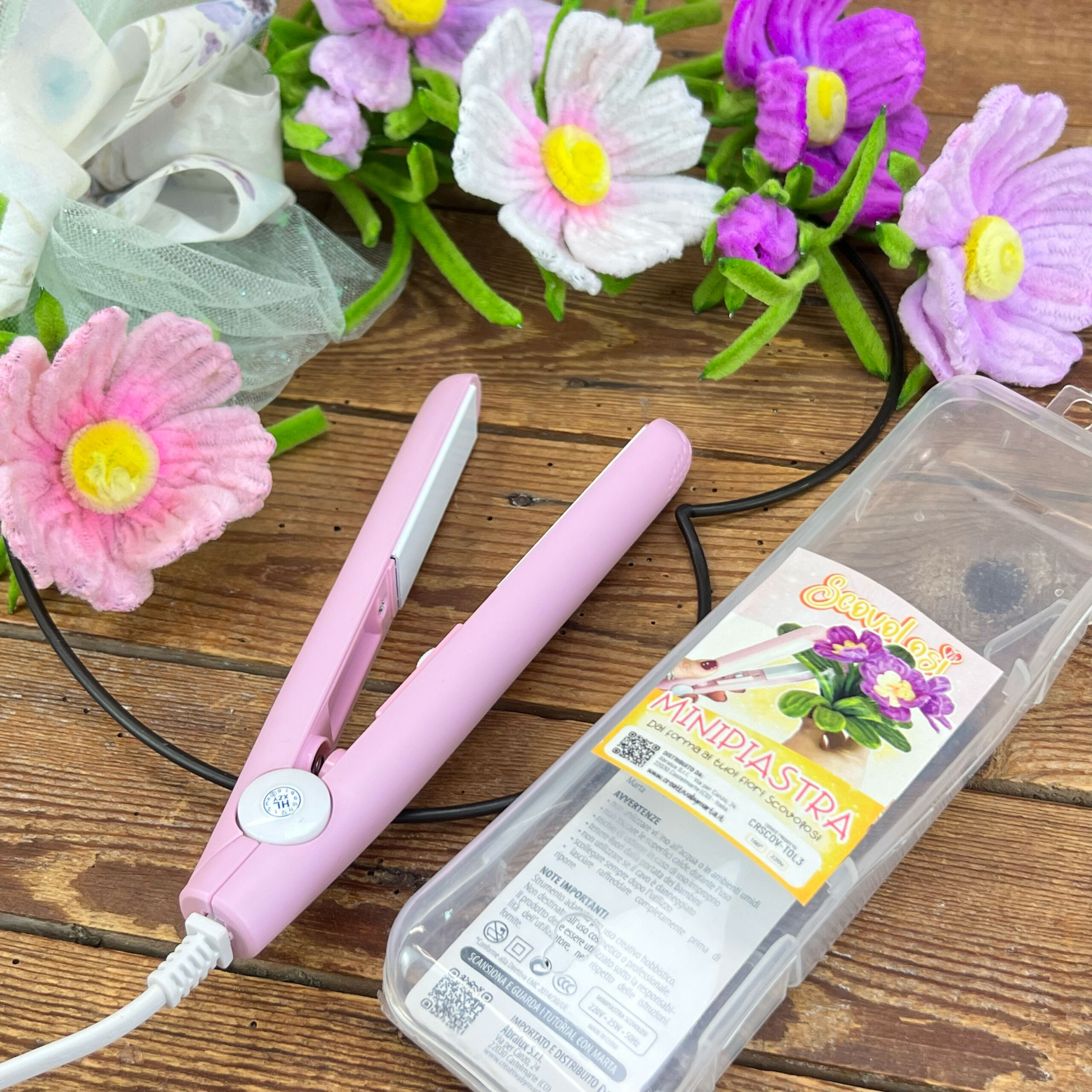 Fiori artificiali e mini piastra rosa su tavolo