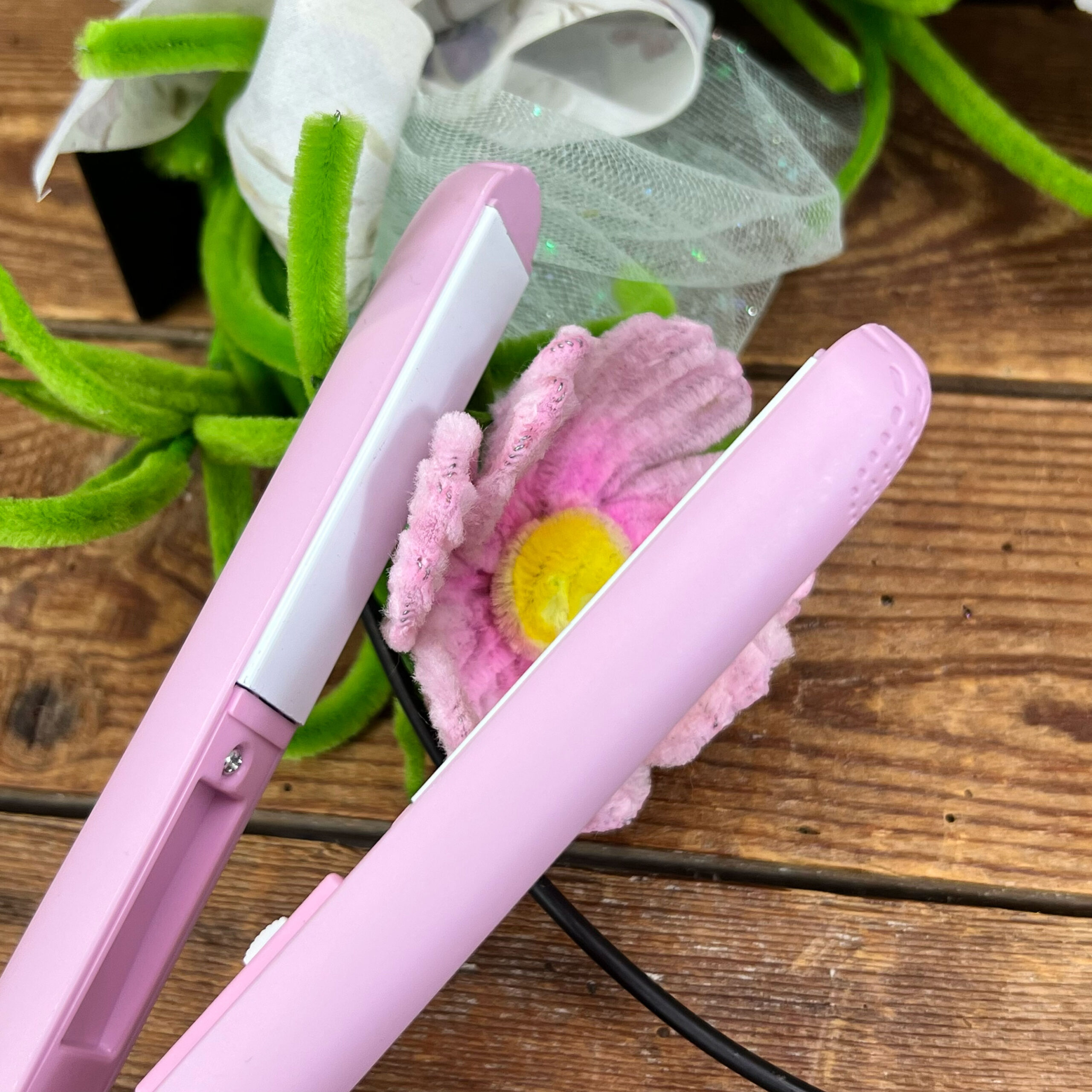 Piastra rosa per capelli su tavolo in legno