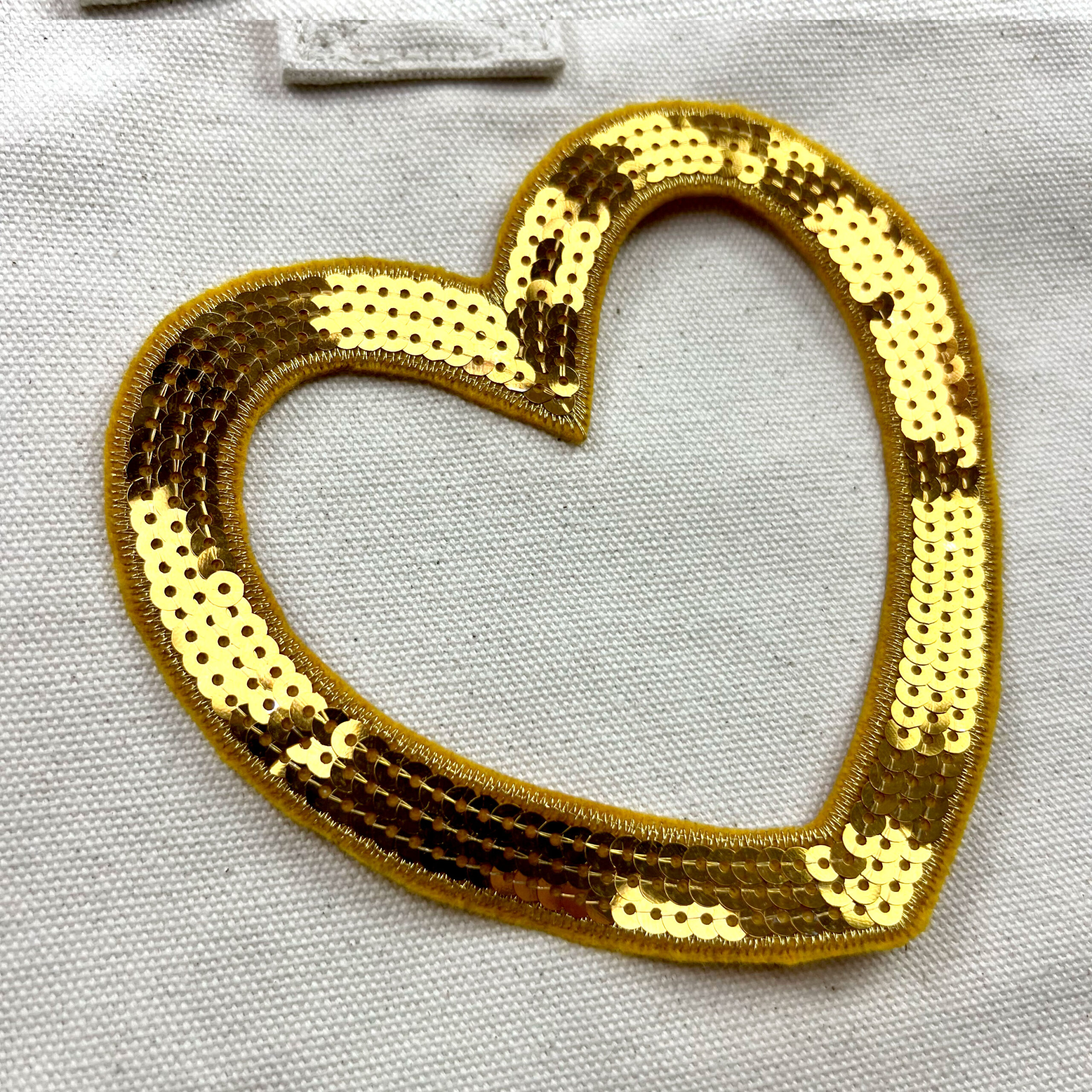 Cuore dorato con paillettes su tessuto bianco