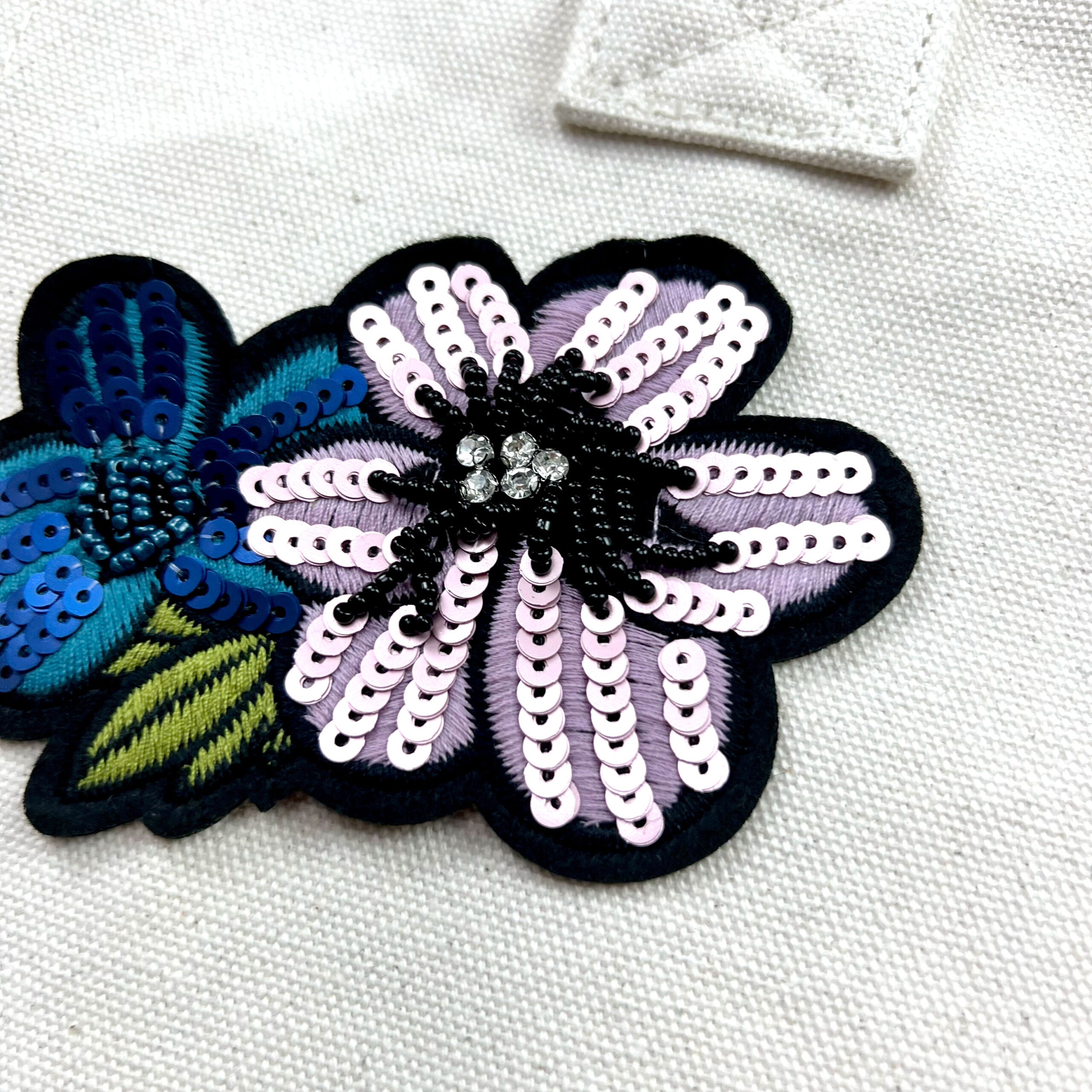 Applicazione floreale ricamata con paillettes su tessuto chiaro