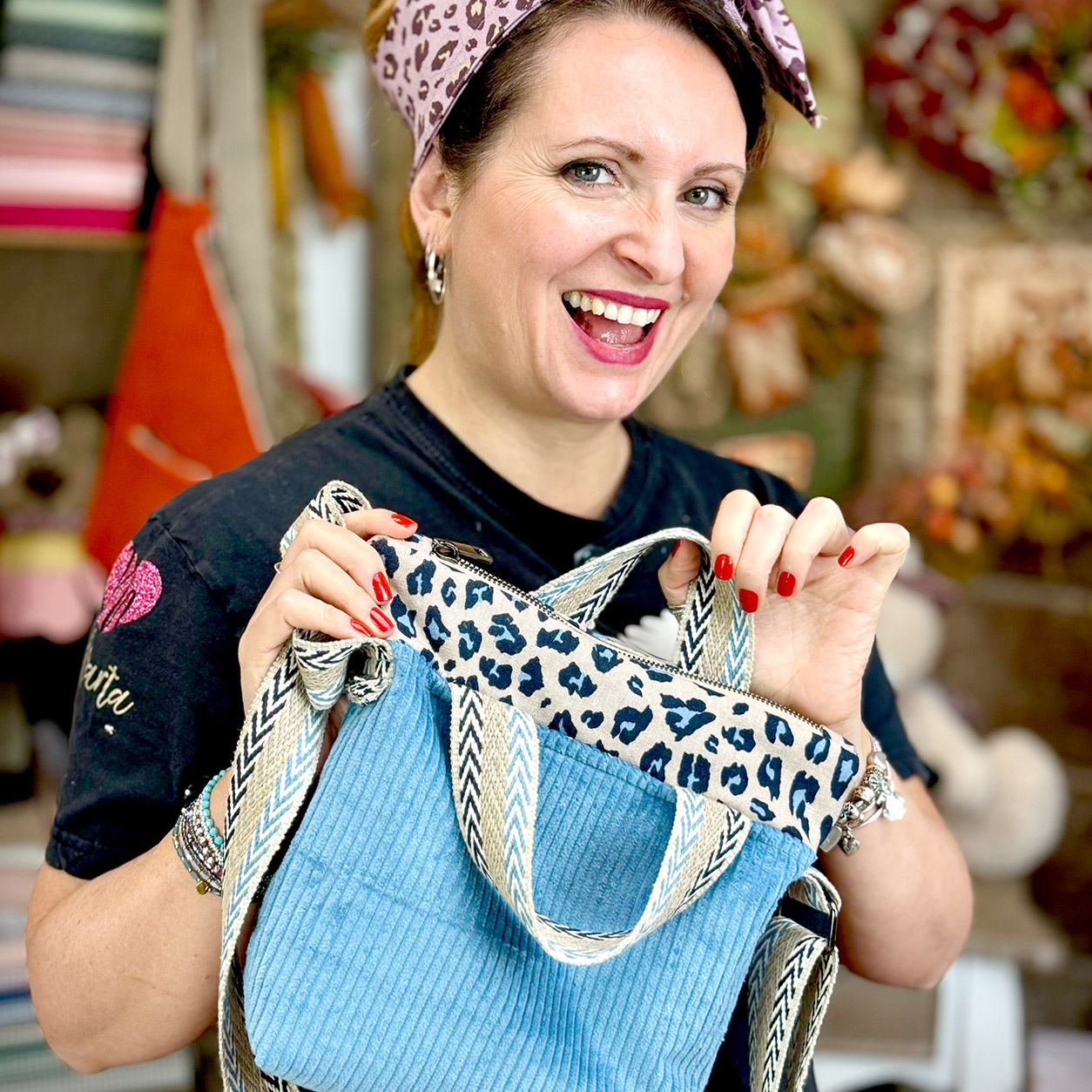 Donna sorridente mostra borsa azzurra con dettagli leopardati